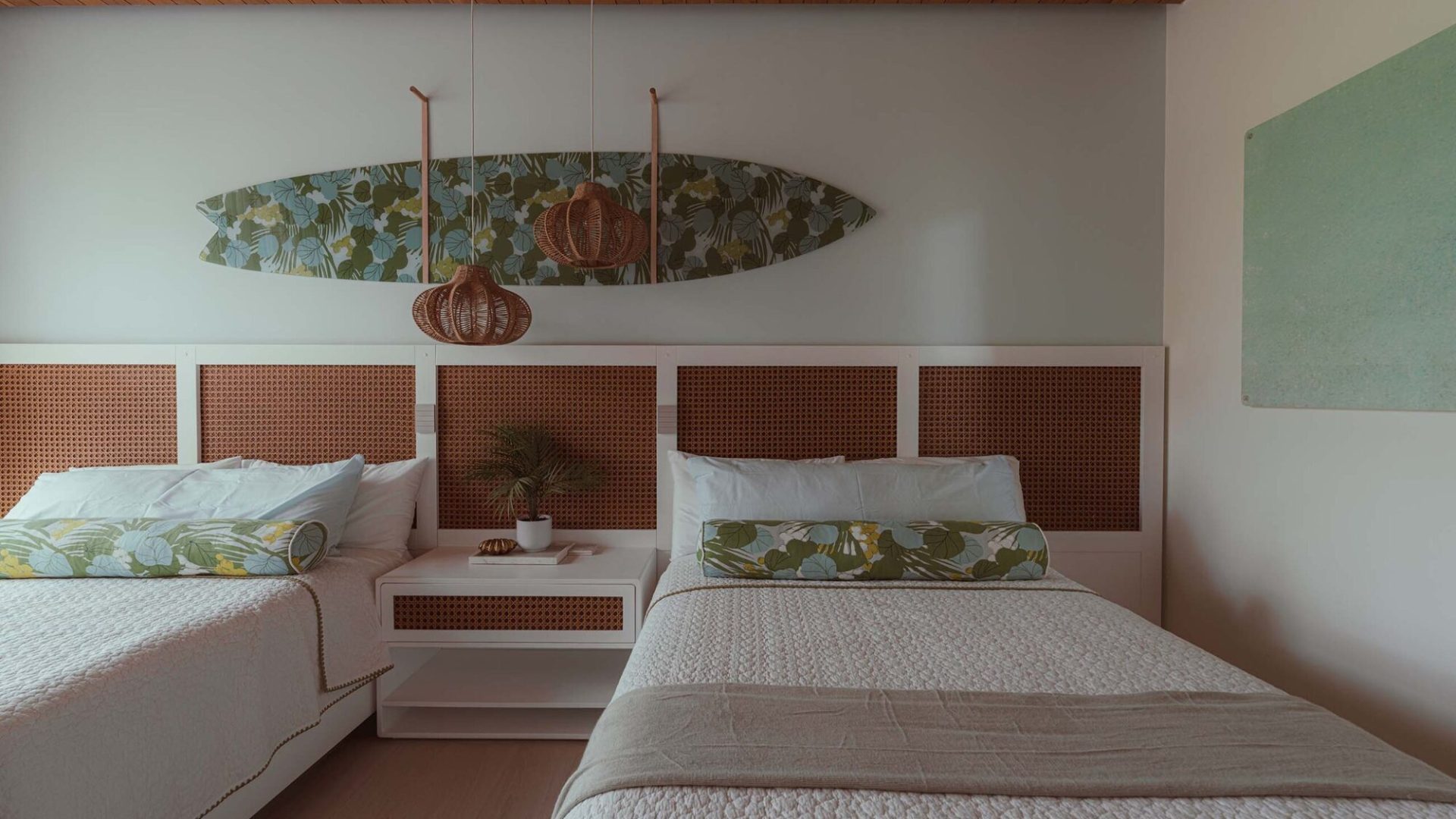 Beach-inspired bedroom with twin beds, wicker pendant lights, and tropical decor elements.