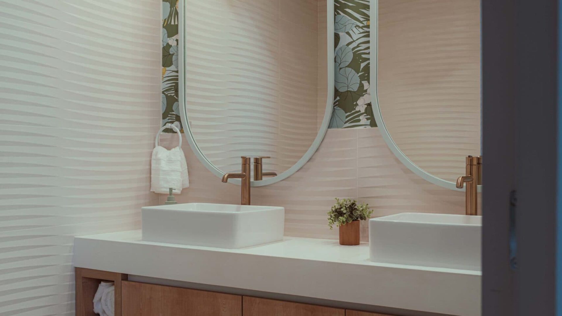 Elegant bathroom vanity with modern sinks and botanical wall decor.