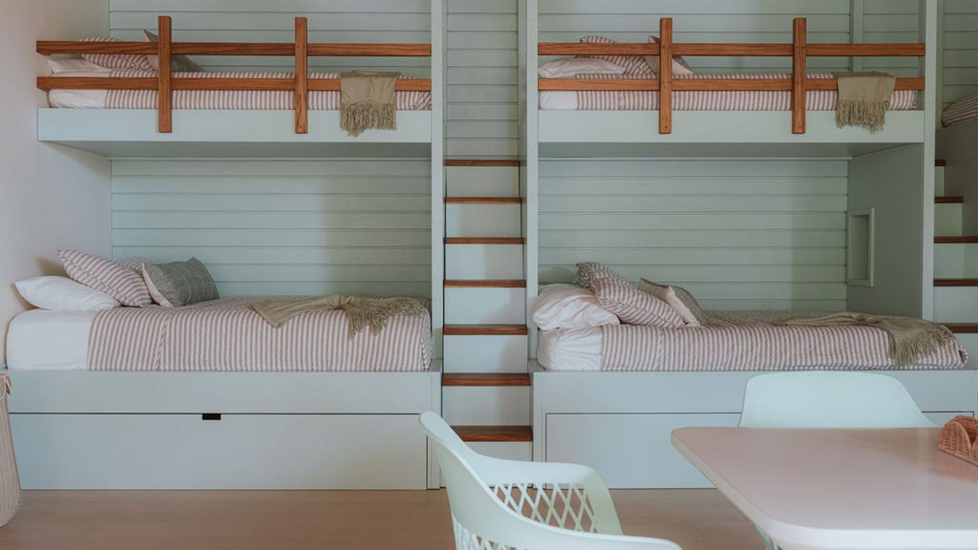 Cozy bunk beds with built-in drawers and a shared staircase in modern bedroom design.