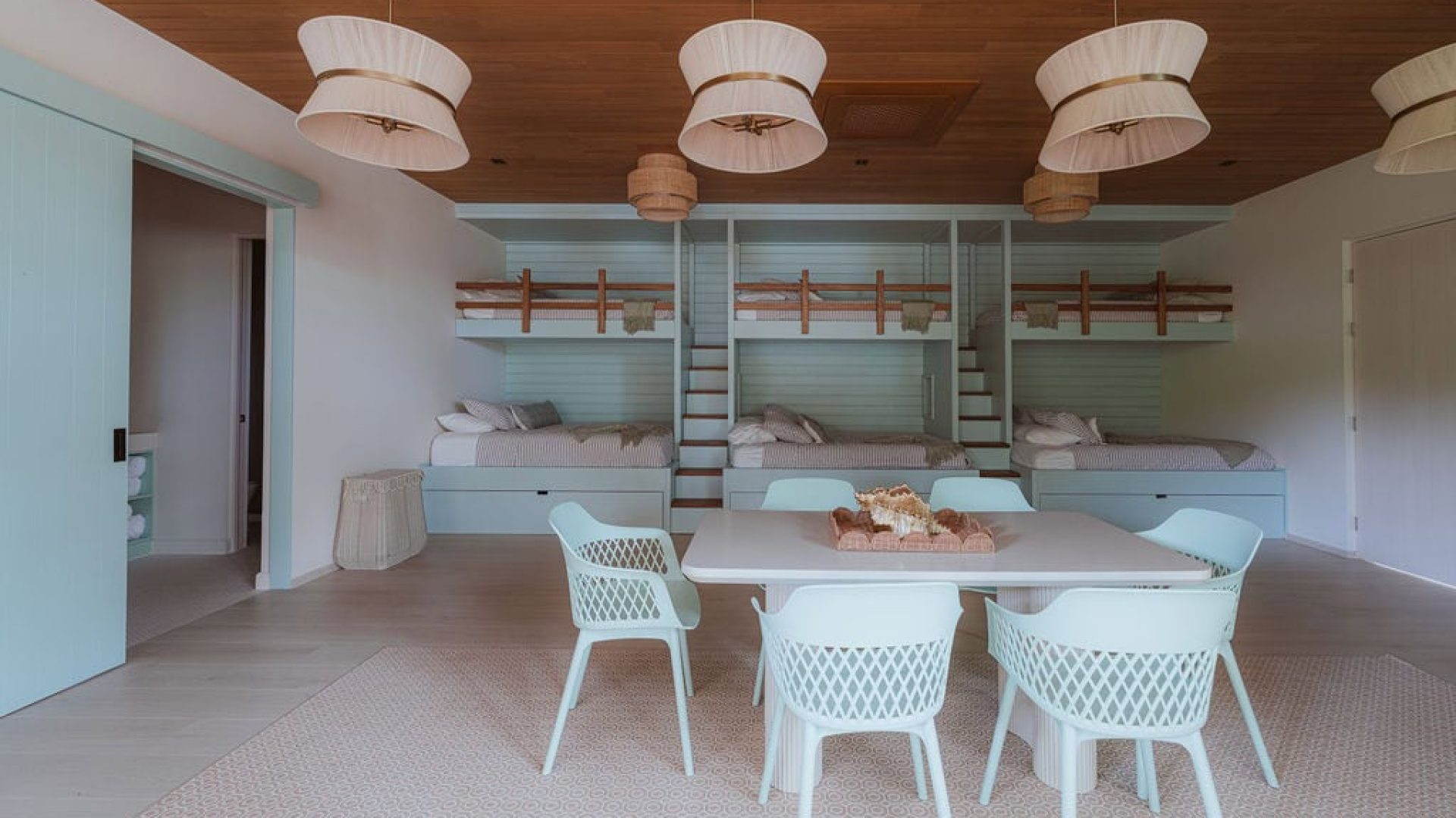 Bright coastal bedroom with bunk beds in a modern beach house, featuring light wood accents and airy decor.