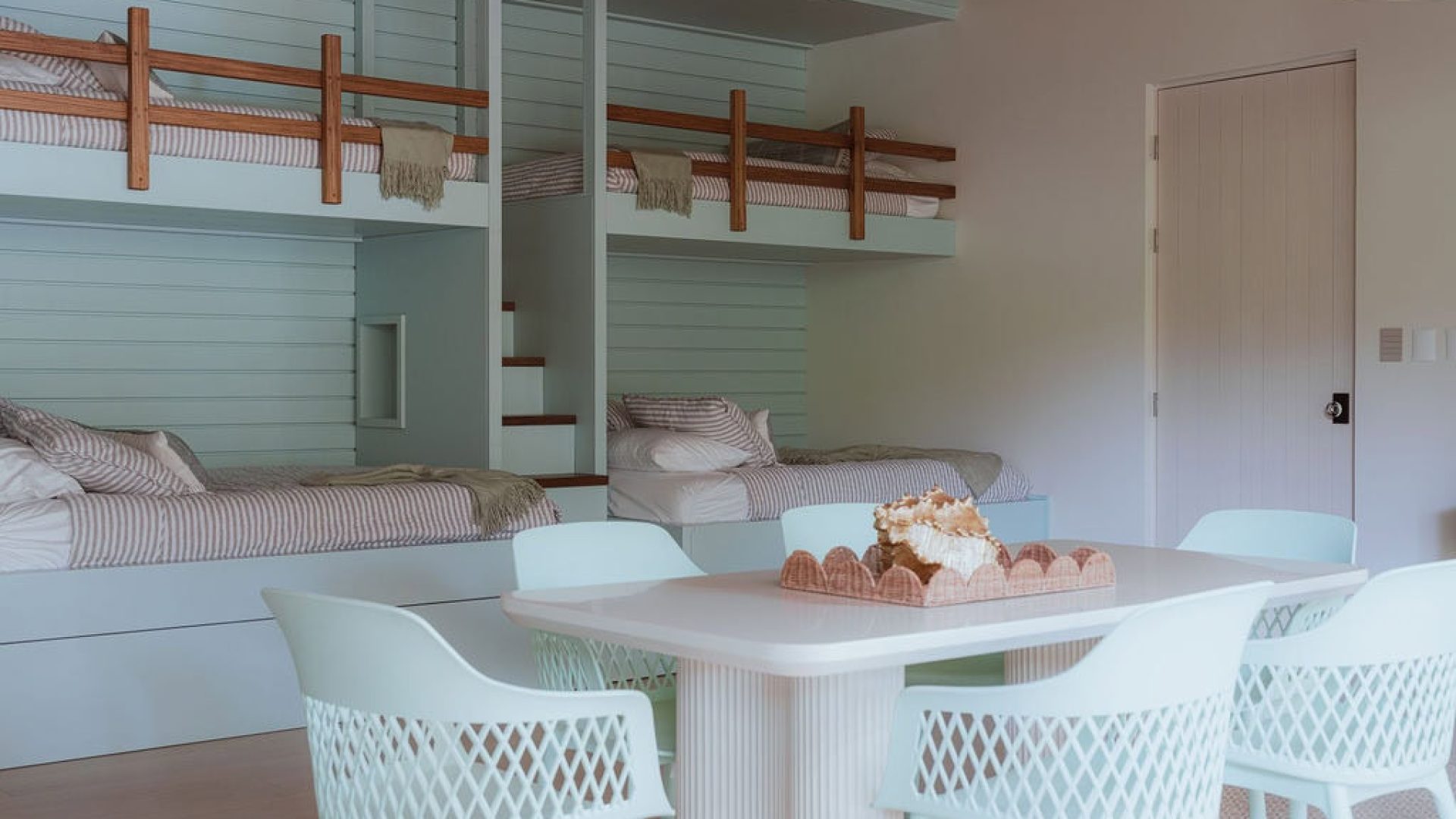 Cozy modern bedroom with bunk beds and white dining table, stylish coastal decor, perfect for beach retreat stays.
