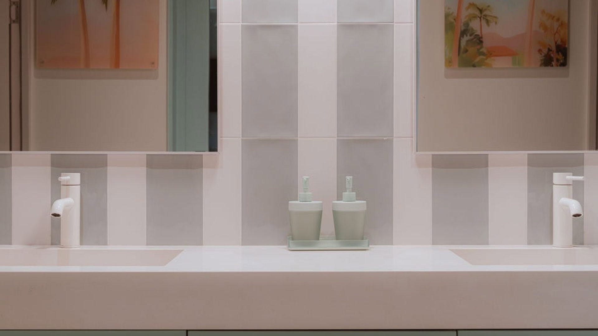 Modern bathroom vanity with twin sinks and tropical-themed artwork, minimalist design with pastel tones.