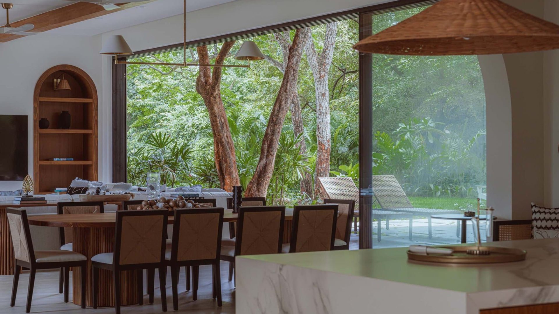 Spacious indoor dining area with large glass windows overlooking lush garden.