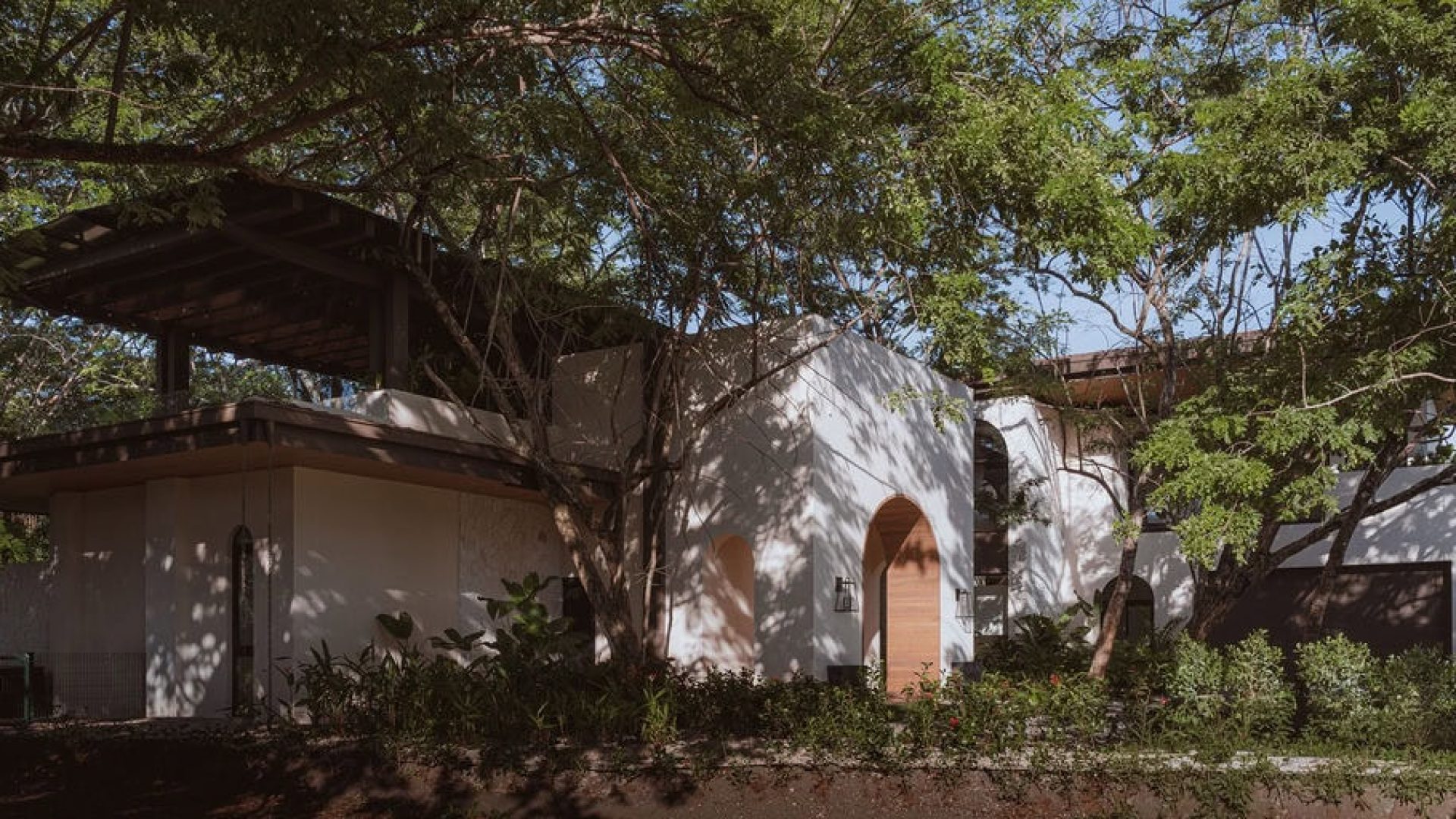 Modern white house surrounded by lush greenery in Vida Pinilla estate.
