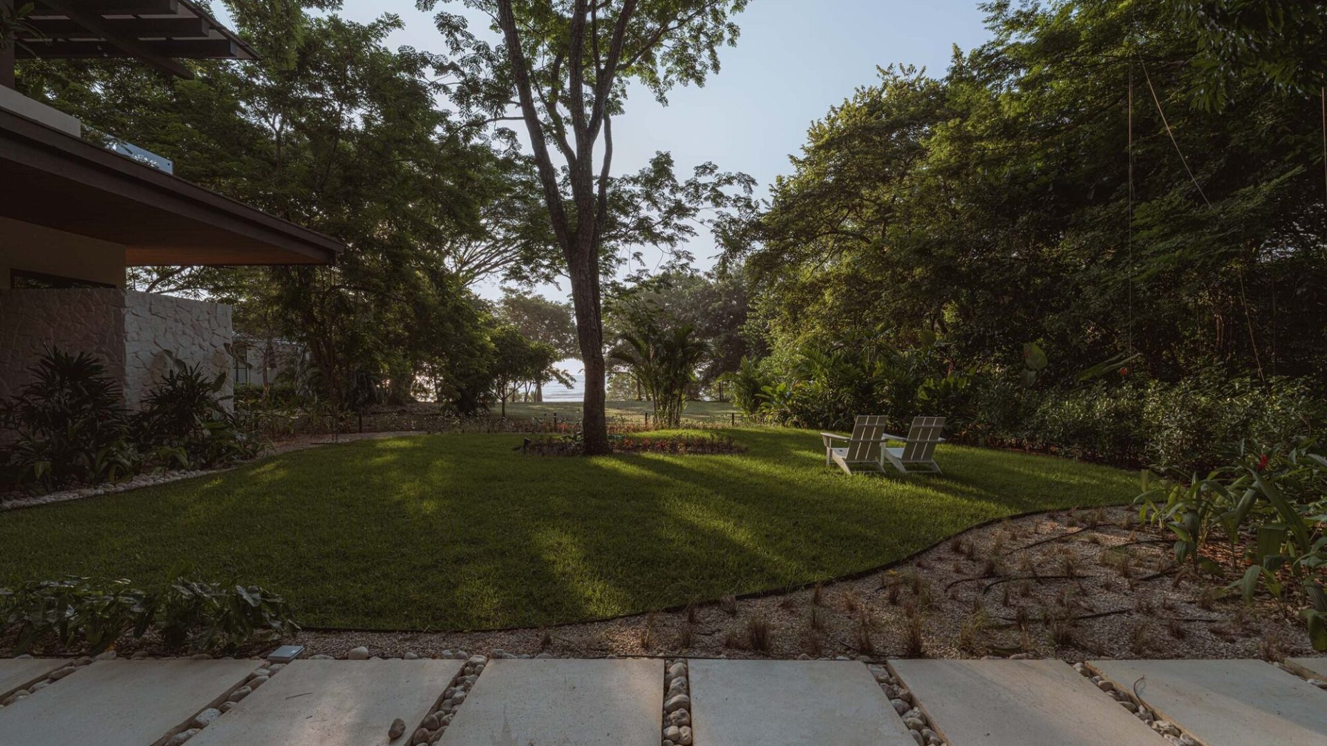 Serene backyard garden with lush green grass and mature trees for outdoor relaxation.