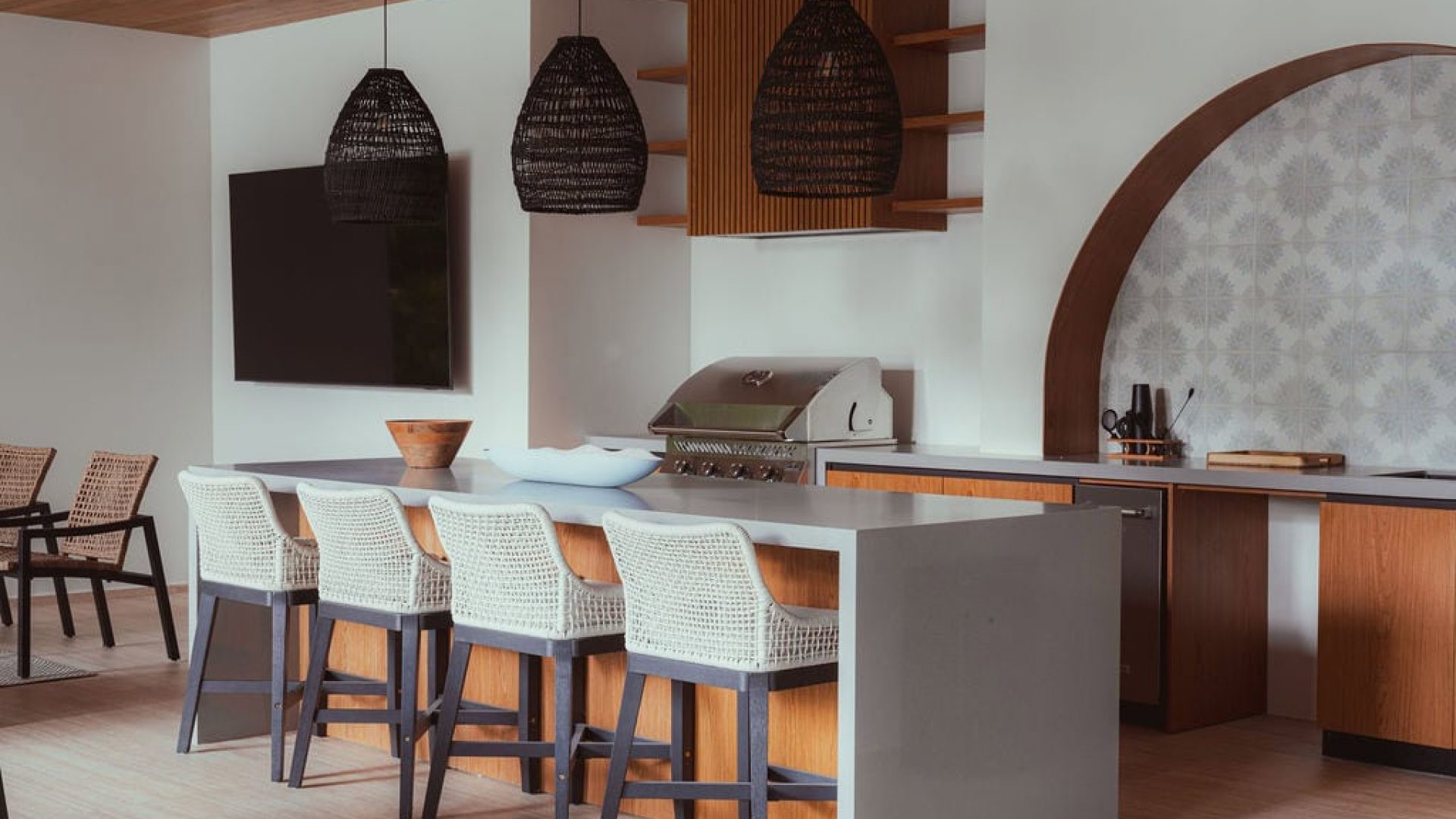 Bright modern kitchen with barstools, pendant lights, and a built-in barbecue for stylish home cooking and entertaining.