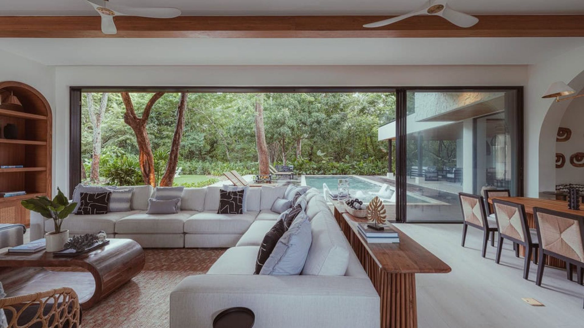 Modern living room with large glass sliding doors overlooking lush outdoor greenery | Vida Pinilla interior design.
