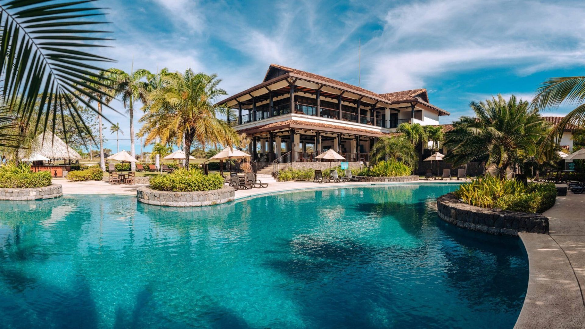 Luxurious hotel with pool, tropical palm trees, and ocean view in a seaside resort.
