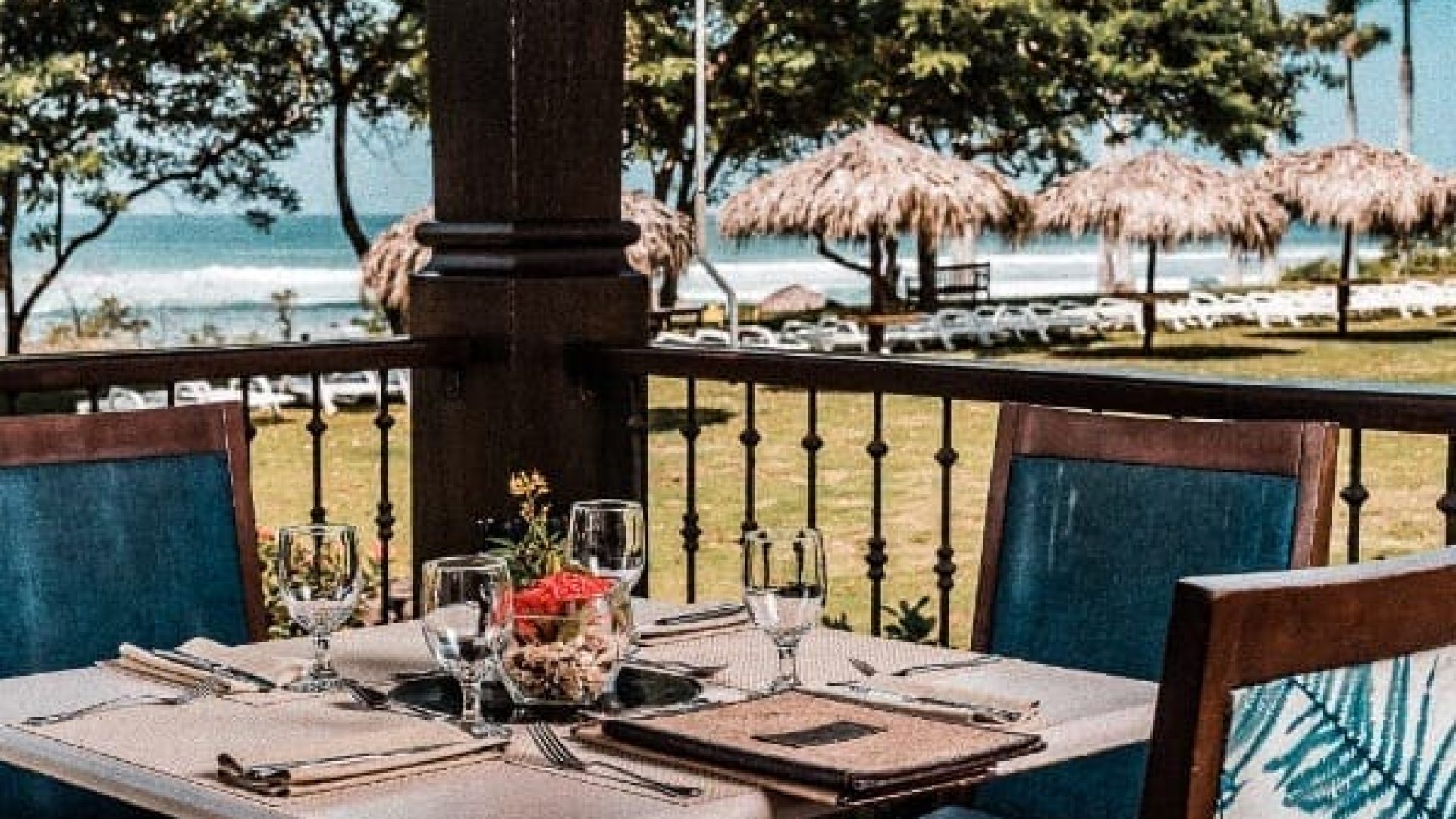A scenic beachside restaurant table set for dining with ocean views and tropical surroundings.