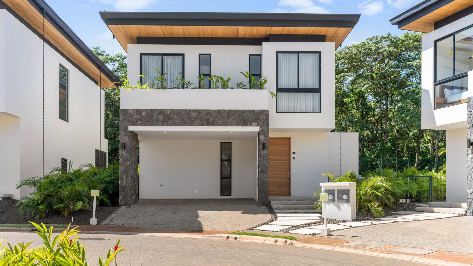 Contemporary modern house with white walls, stone accents, and lush greenery, located in Vida Pinilla.
