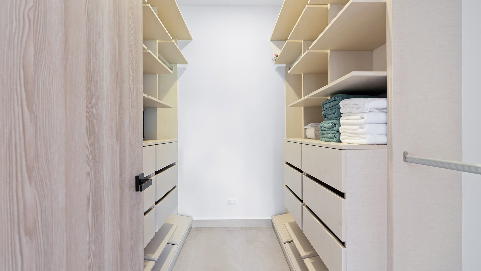 Organized walk-in closet with shelves and drawers, featuring neatly folded towels and clothing, showcasing modern storage solutions.