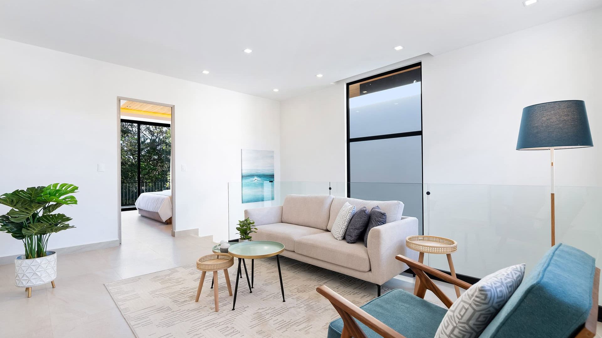 Bright modern living room with large windows overlooking greenery, stylish furniture and minimalistic decor.