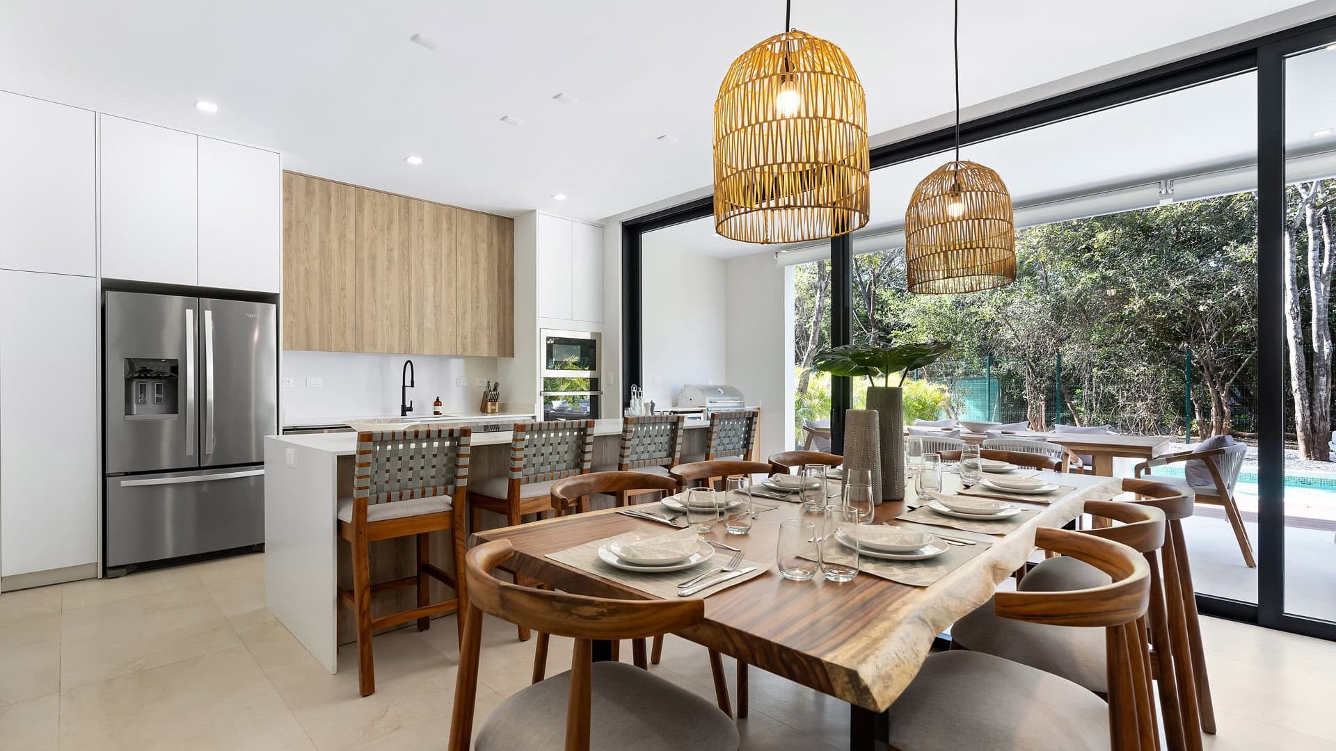 Modern open-concept kitchen and dining area at Vida Pinilla with stylish wood accents and large glass doors.