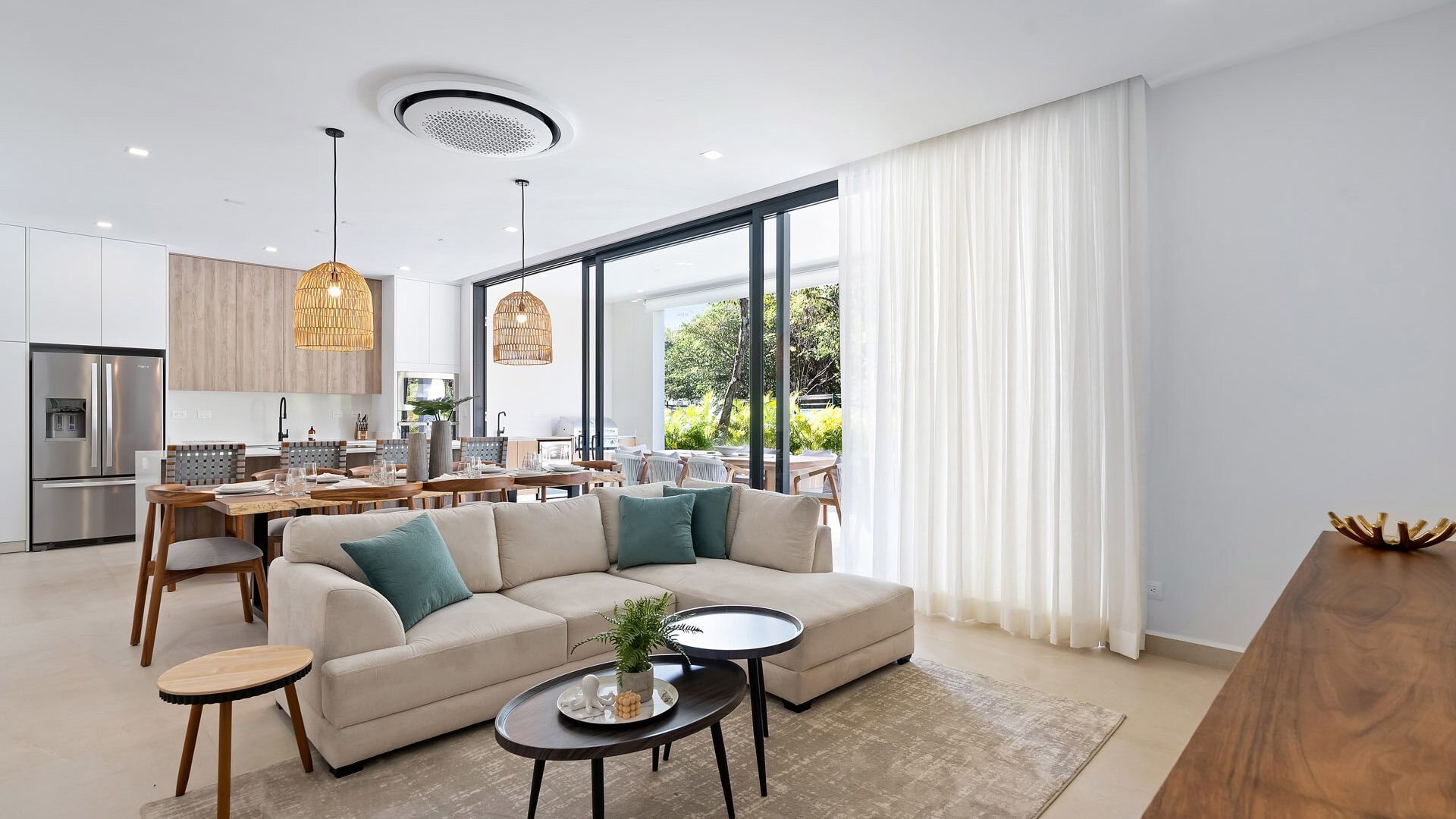 Modern living room and open-concept kitchen with sleek design and natural light, featuring comfortable seating and stylish decor.