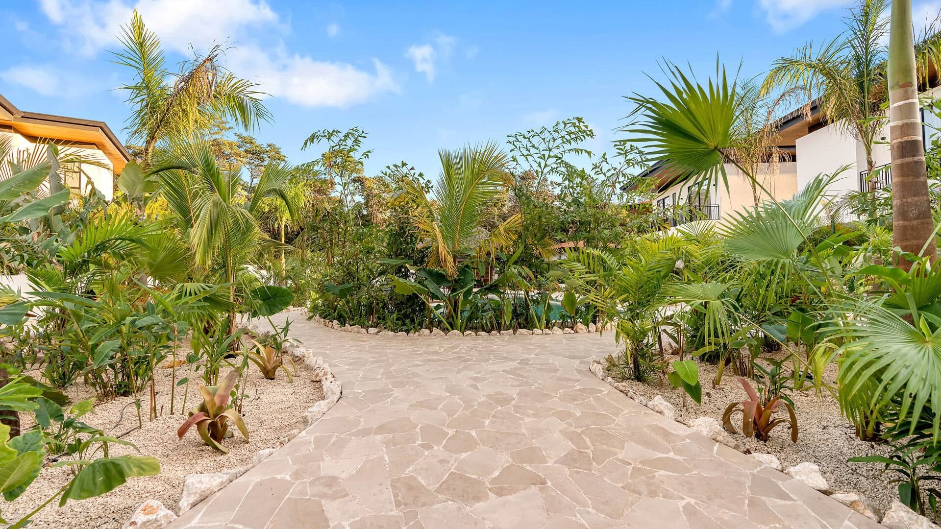Lush tropical garden with a stone pathway and vibrant greenery at Vida Pinilla, providing a relaxing paradise setting.