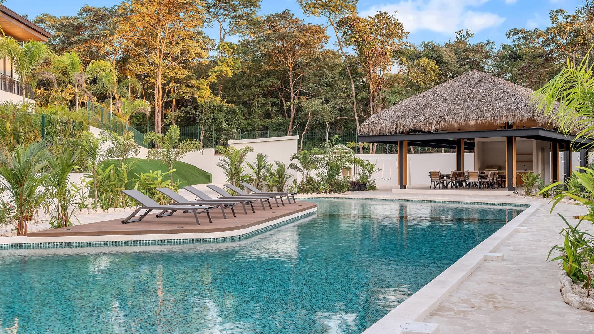 Luxurious swimming pool surrounded by lush tropical greenery and outdoor lounging area at Vida Pinilla.