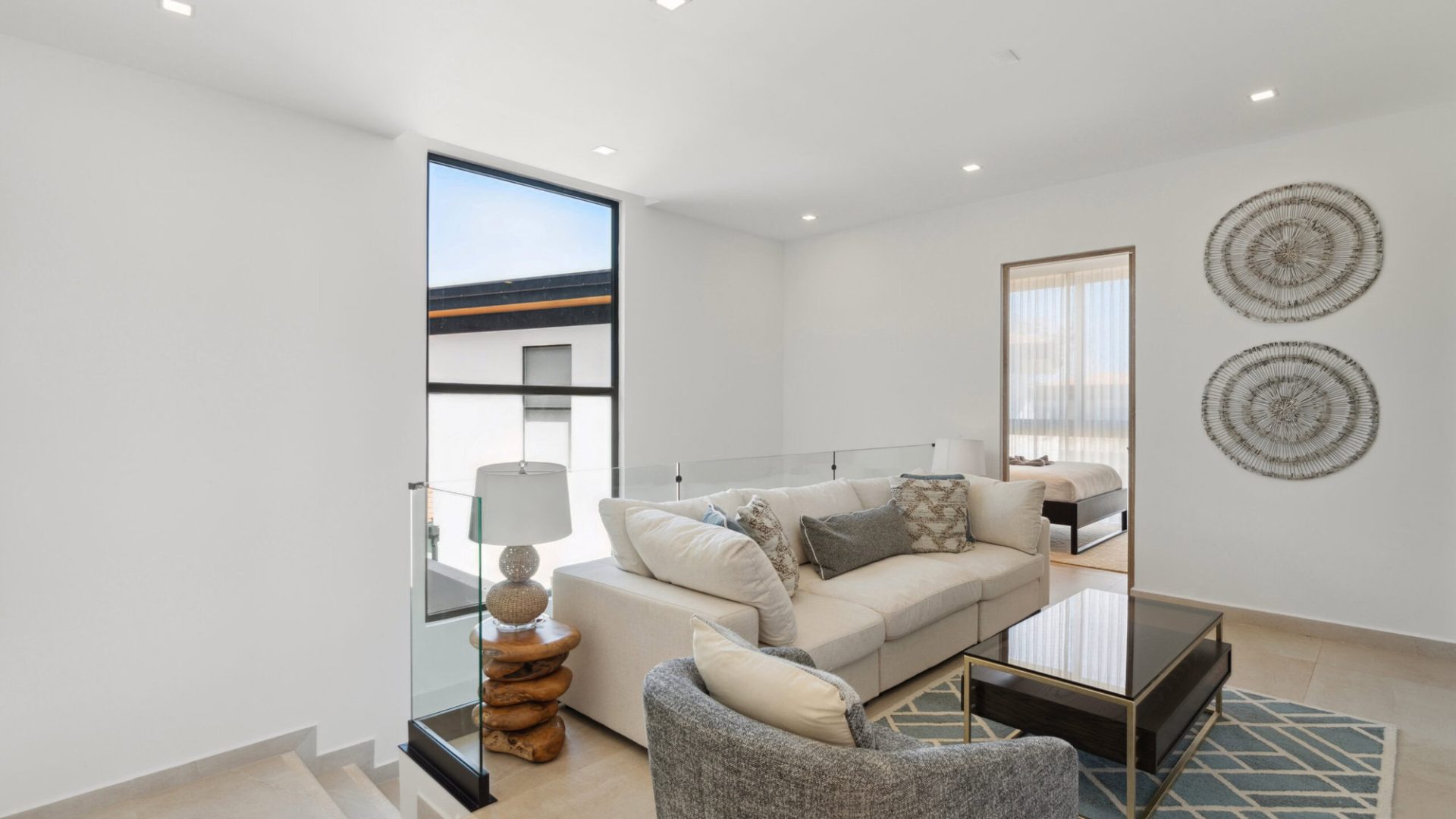 Bright modern living room with white sofa, contemporary decor, and large windows in a stylish home.