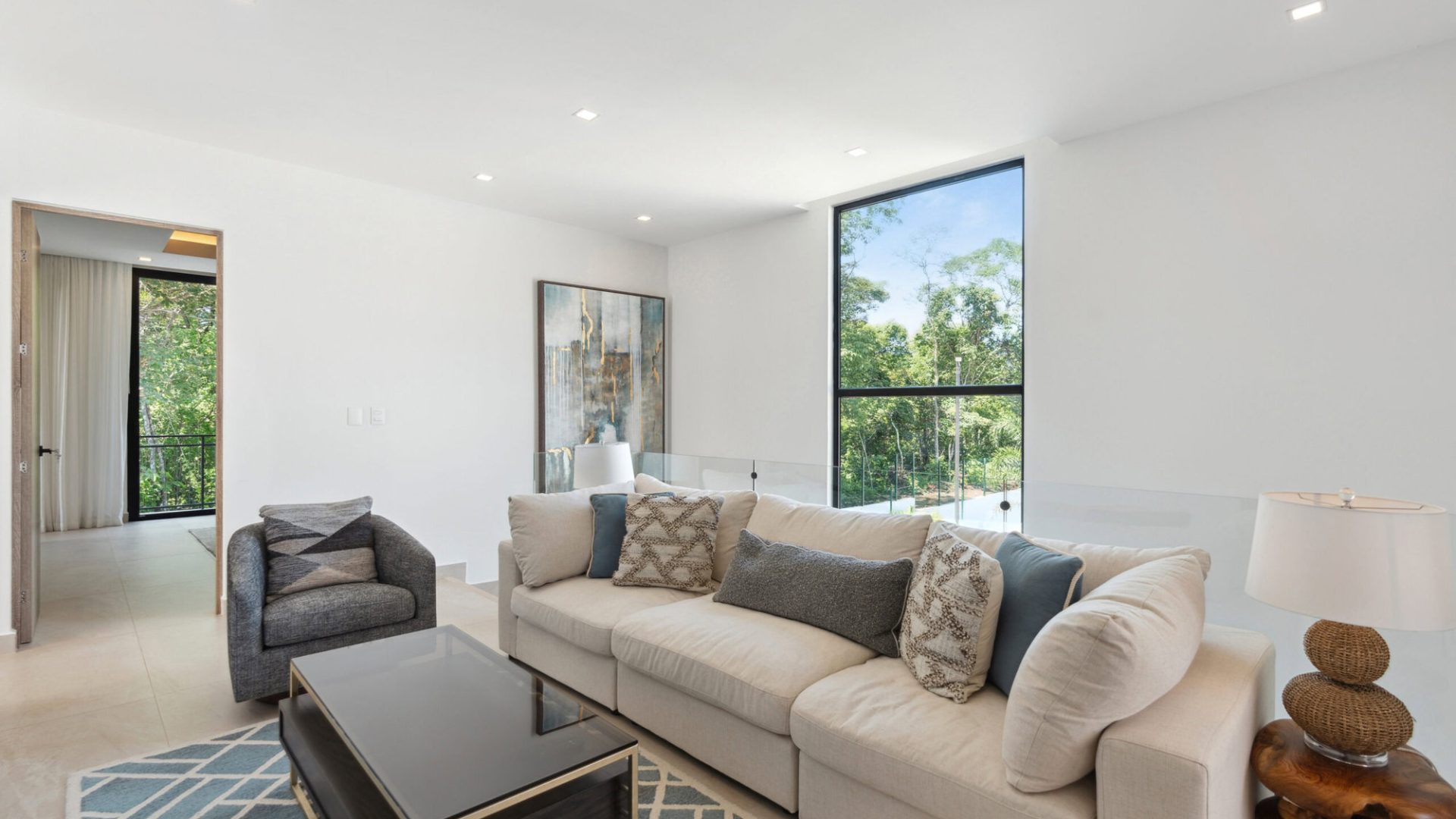 Bright living room with large window overlooking lush greenery, modern furnishings, and calming decor.