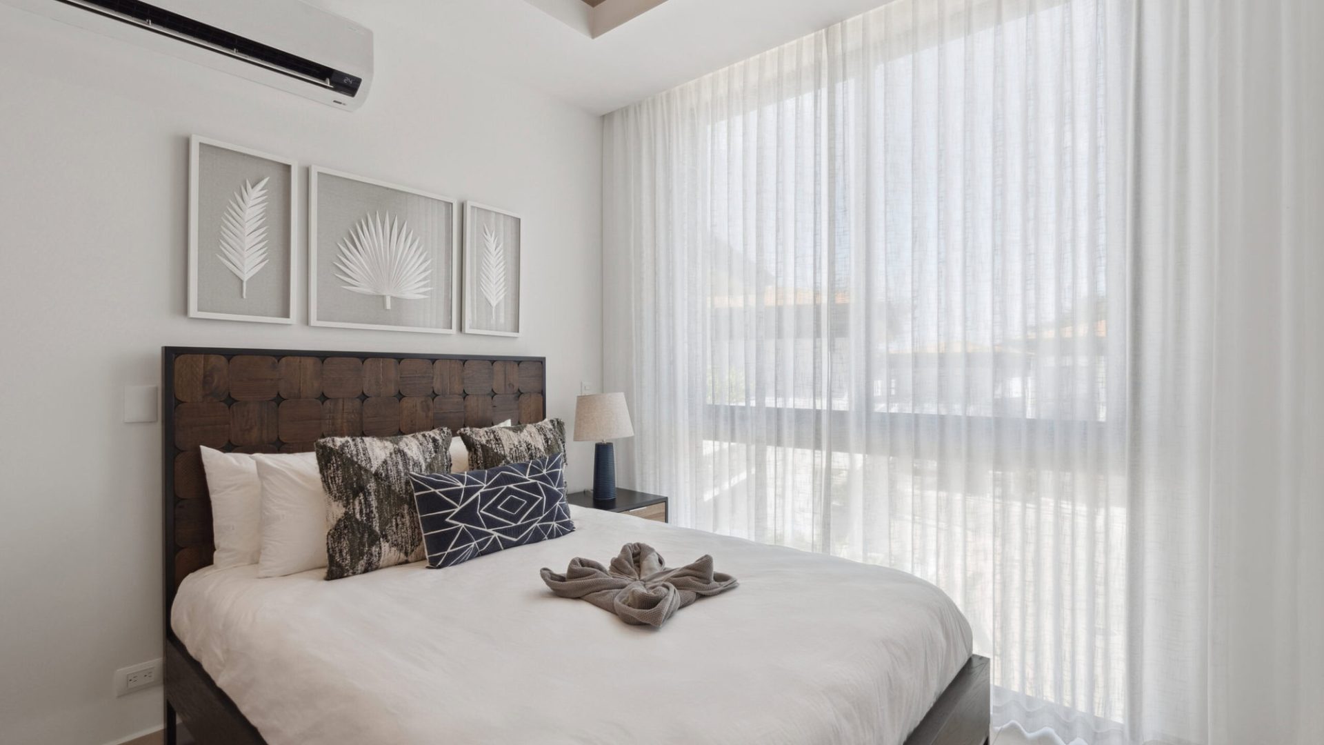 Bright modern bedroom with large window, white curtains, and stylish decor.