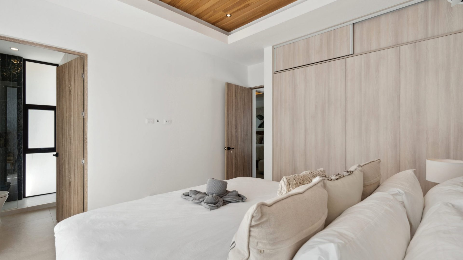 Luxurious bedroom with wooden accents and white decor, perfect for relaxation.