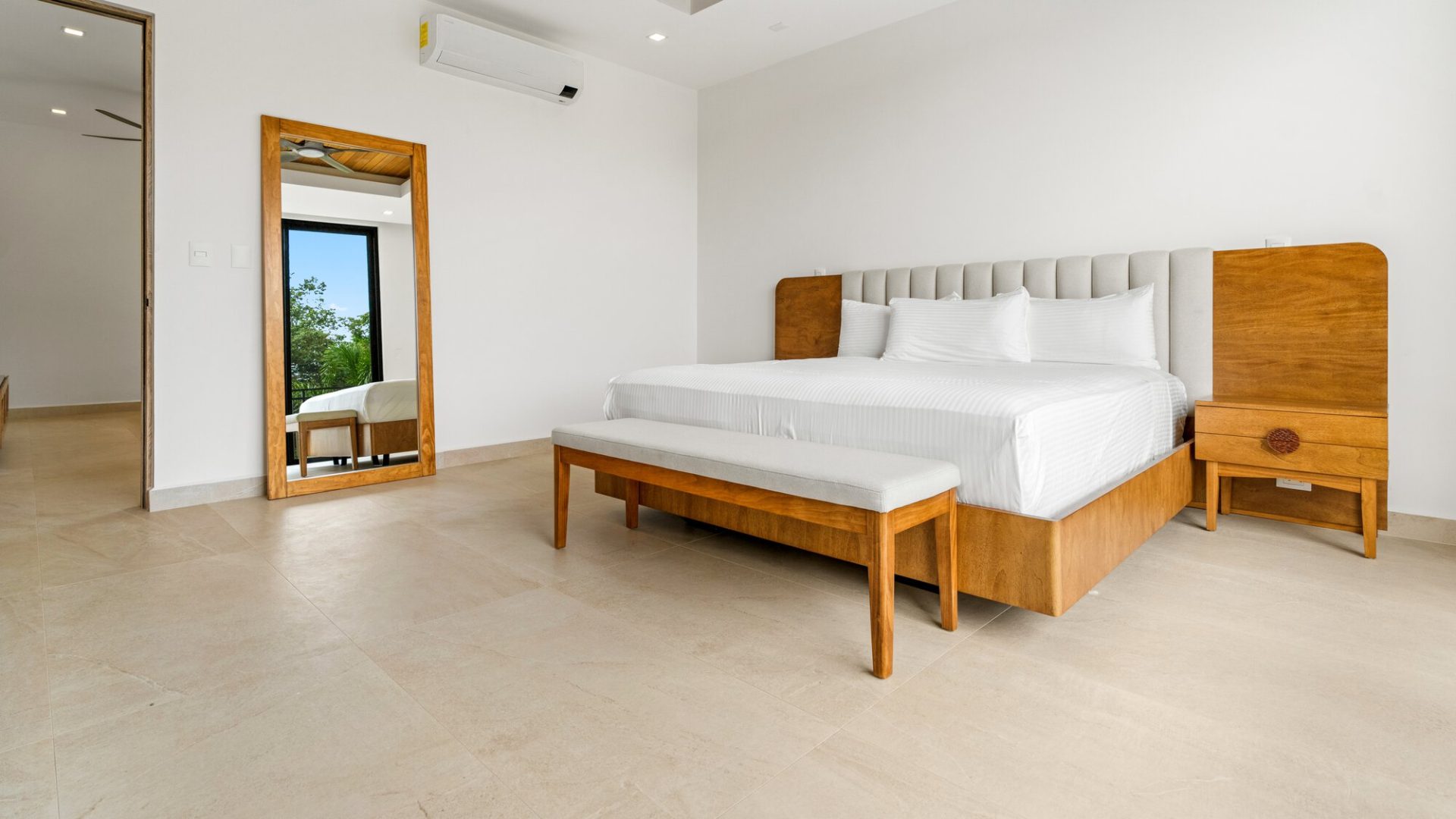 Modern hotel bedroom with wooden furniture and white bedding, bright and minimalist design.