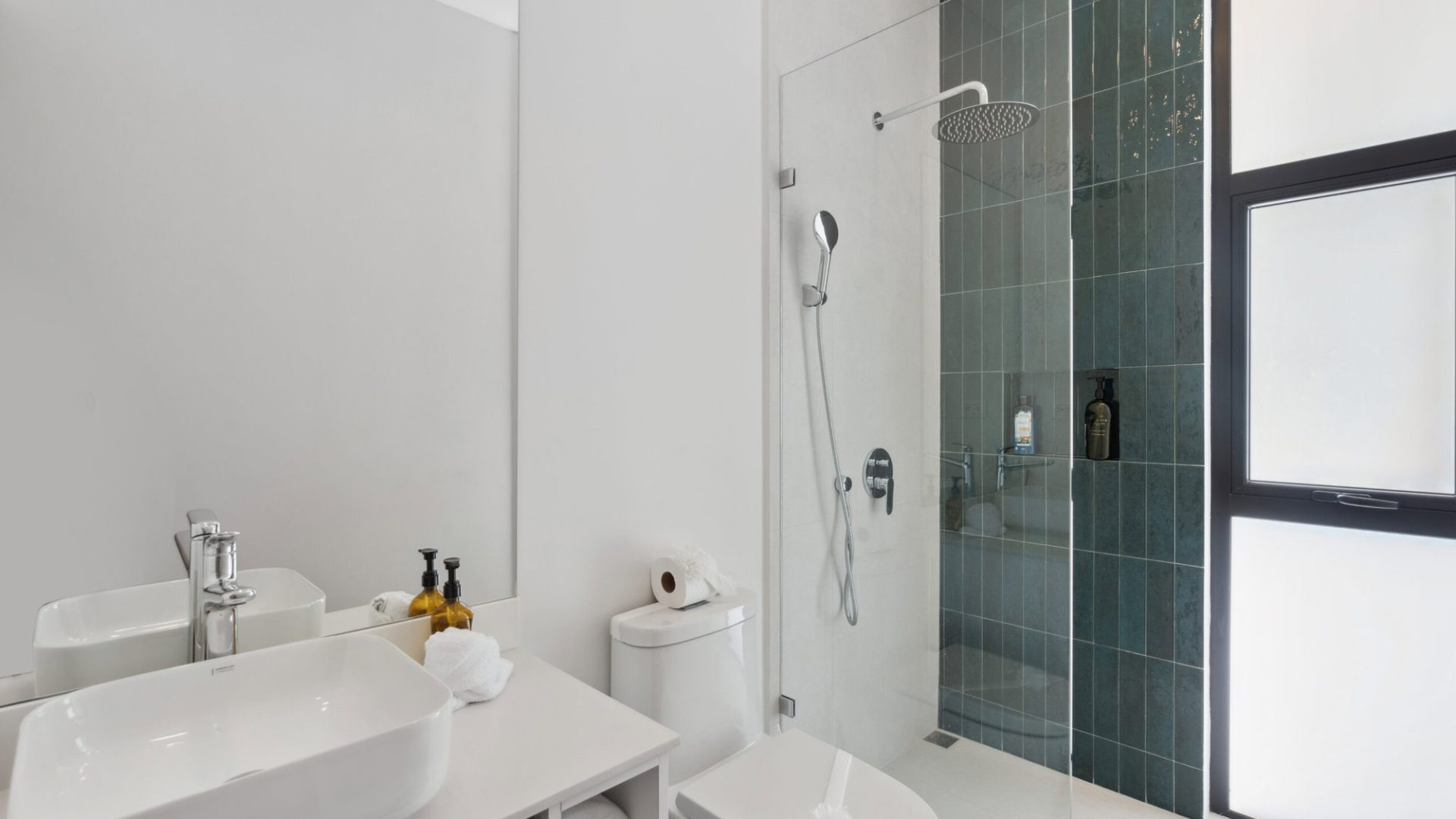 Modern minimalist bathroom with sleek white sink and glass shower enclosure for a stylish, functional space.
