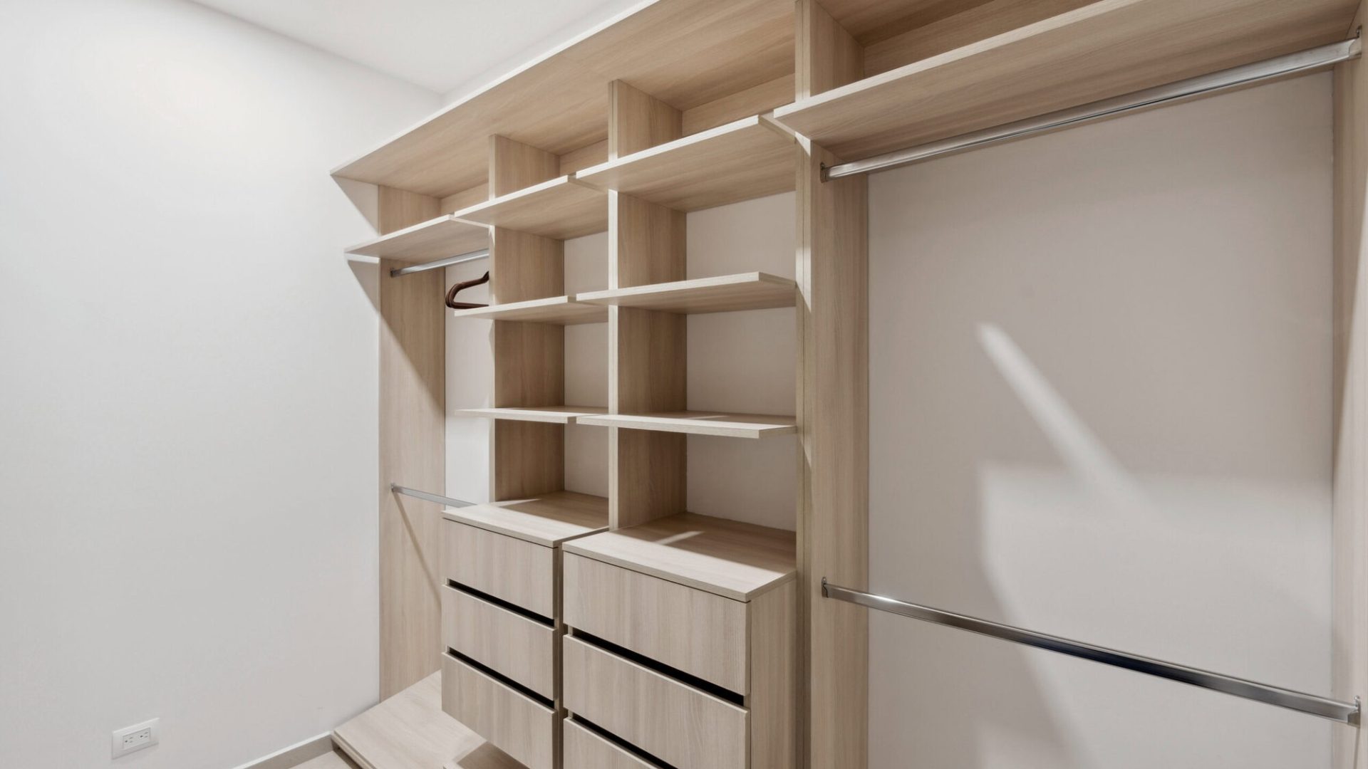 Custom walk-in closet with light wood shelving and drawers for organized storage.