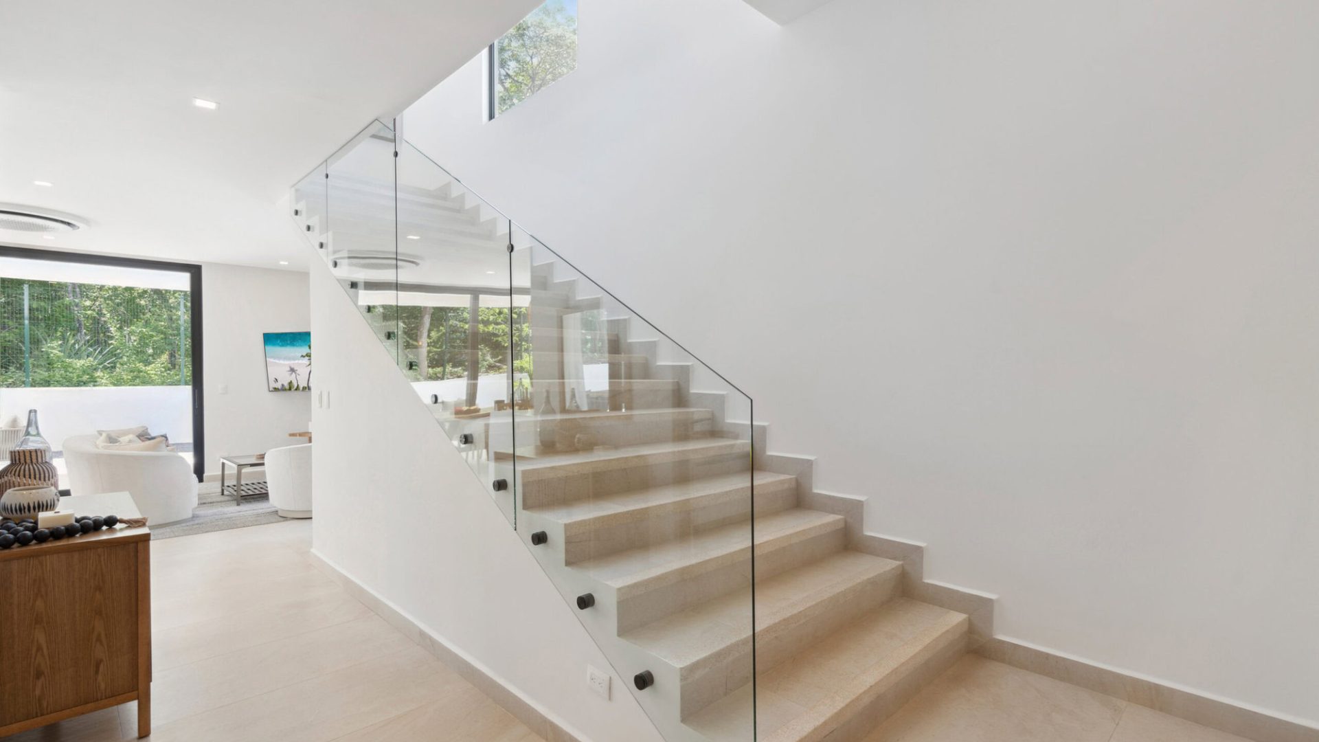 Sleek modern staircase with glass railing in a minimalist home interior.