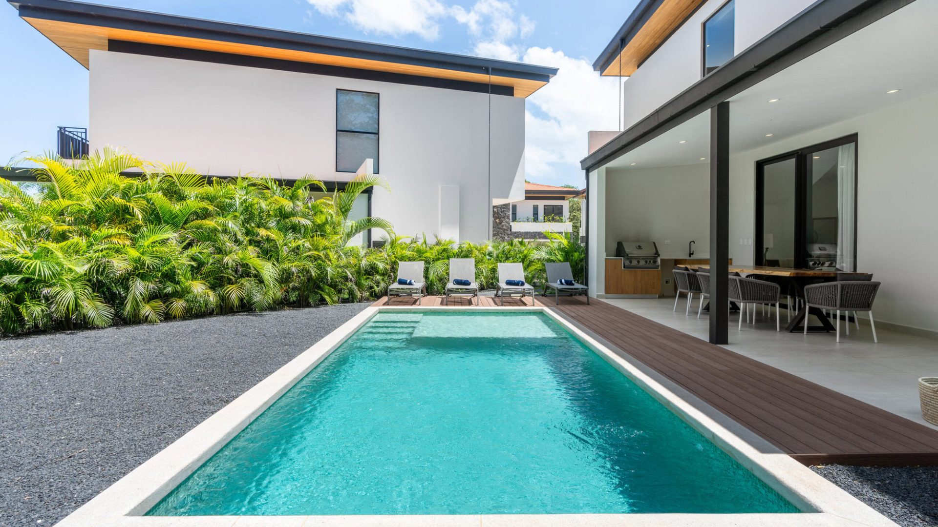 Luxurious modern home with swimming pool, outdoor dining area, and tropical landscaping.