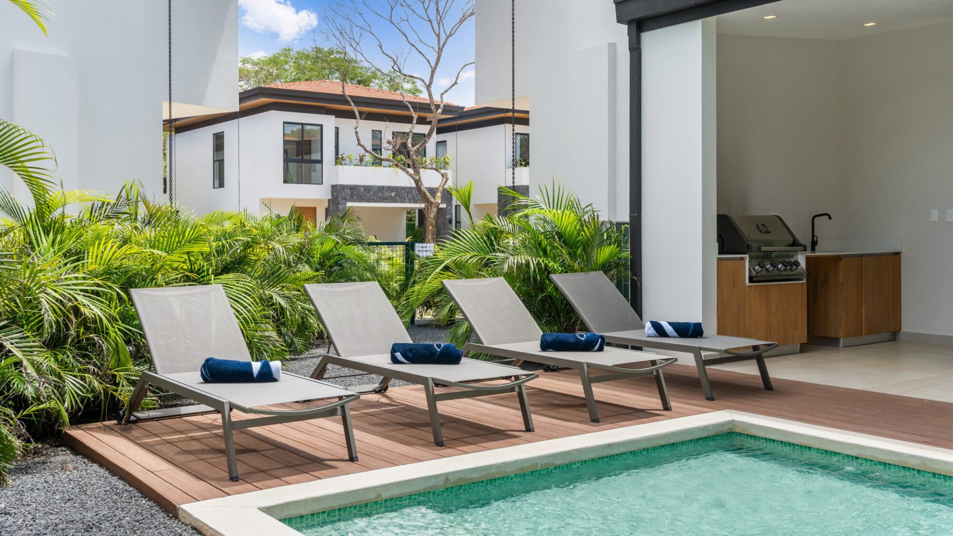 Sun loungers by a private pool with lush greenery at Vida Pinilla luxury residential area.