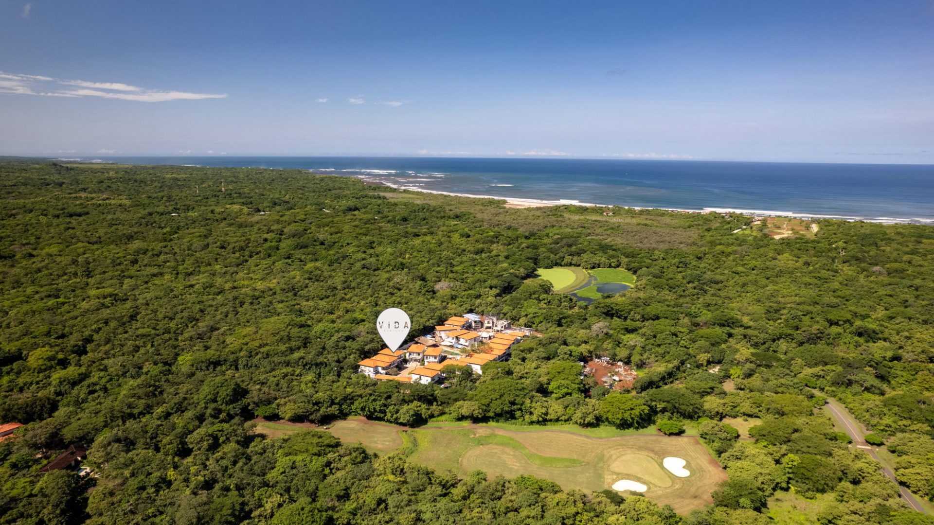 Aerial view of Vida Pinilla beachfront property surrounded by lush green forest and golf course, overlooking the ocean.