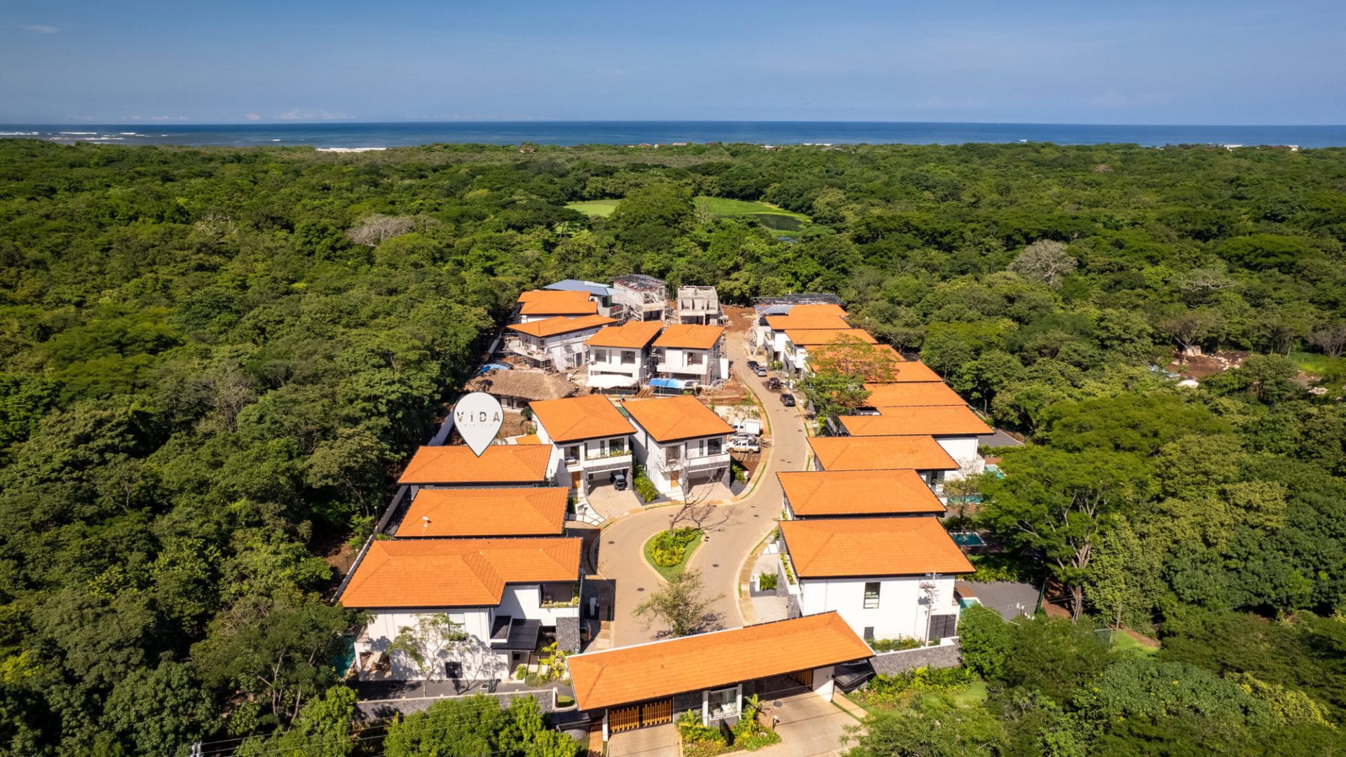 Modern townhouse community near the coast with lush green surroundings and orange-tiled roofs.