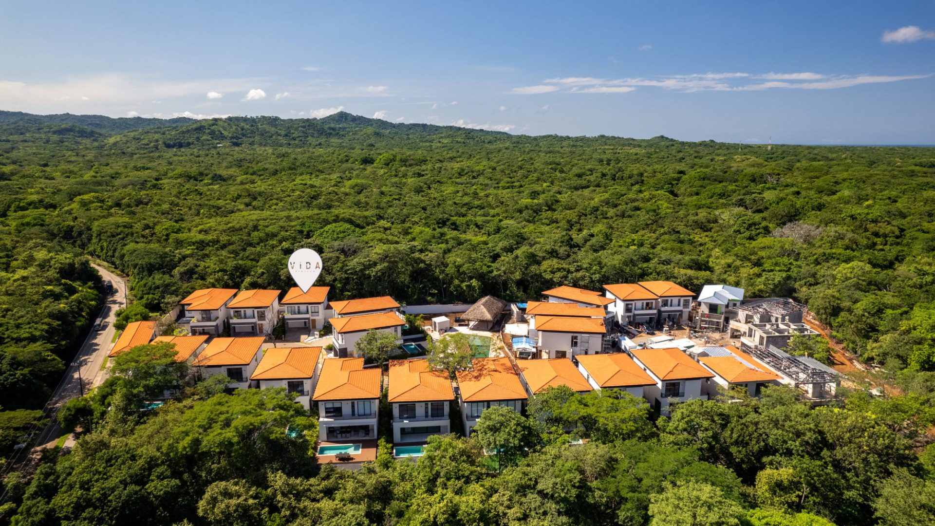 Aerial view of Vida Pinilla luxury homes surrounded by lush green forest and mountains in Costa Rica.