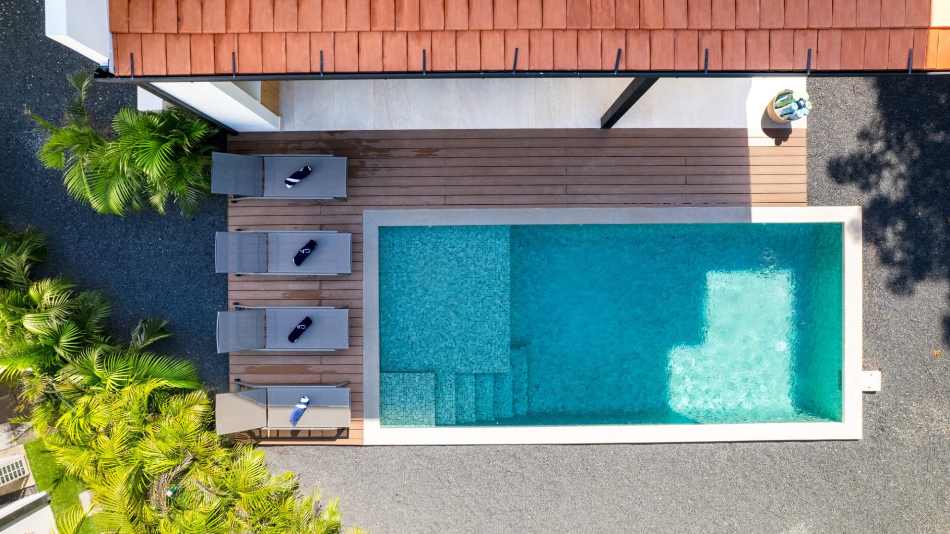 Relaxing backyard pool with surrounding lounge chairs and lush tropical greenery.