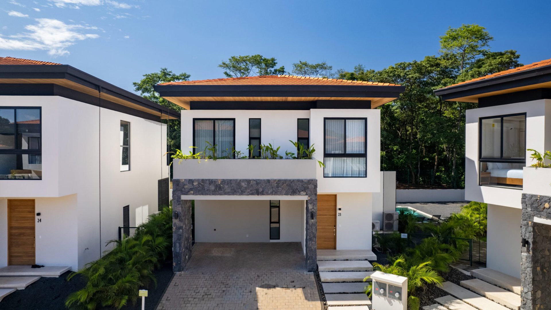 Modern luxury villa with contemporary design, white exterior, stone accents, and lush landscaping.