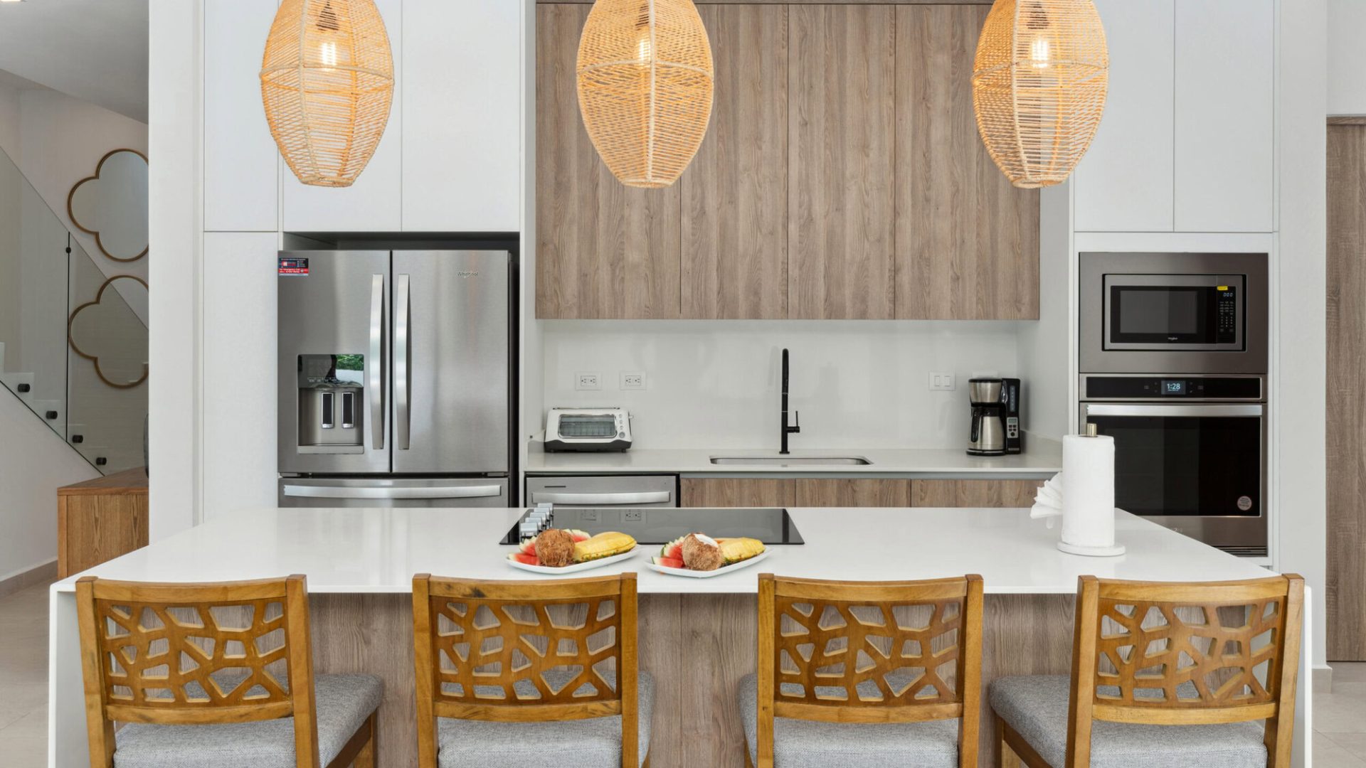 Modern kitchen with white and wooden cabinetry, stainless steel appliances, and woven pendant lighting.