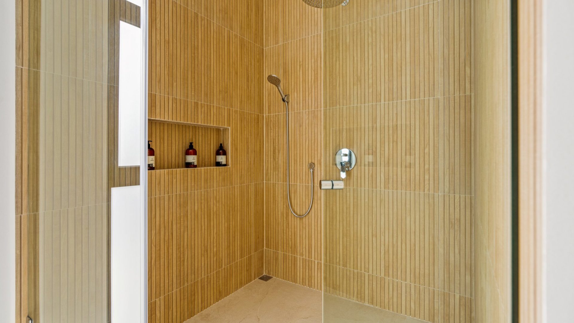 Luxurious wooden-tiled shower with built-in shelf and modern fixtures.