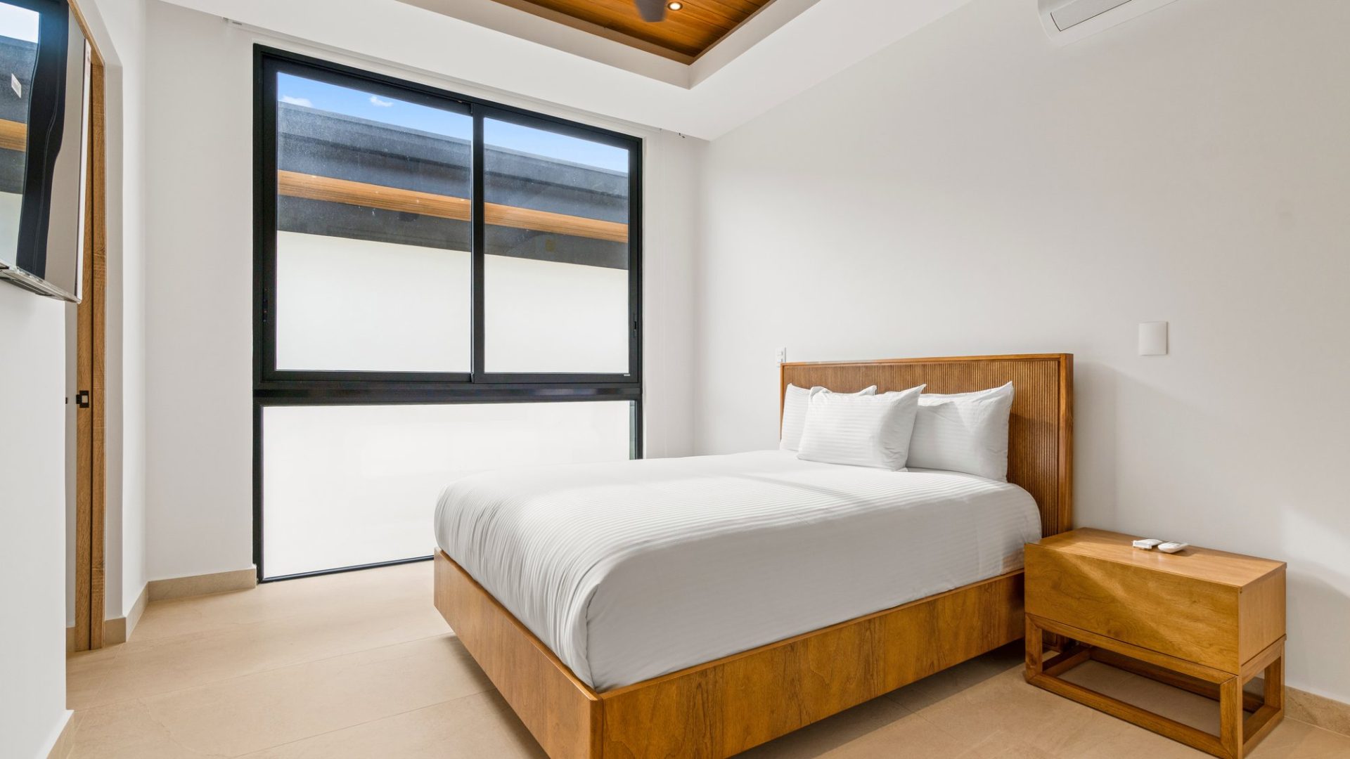Modern minimalist bedroom with wooden furniture and large window, relaxing and bright interior for ultimate comfort.