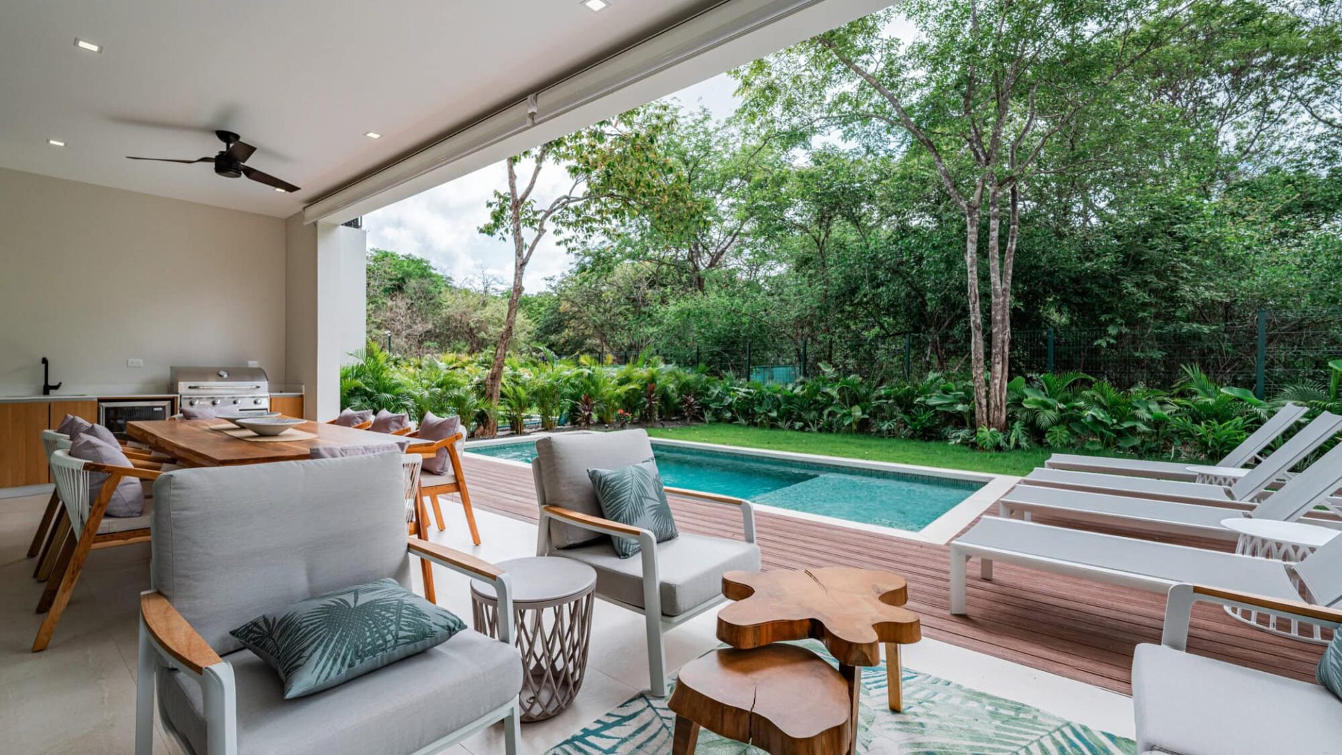 Modern outdoor living space with pool, lush greenery, and stylish patio furniture.