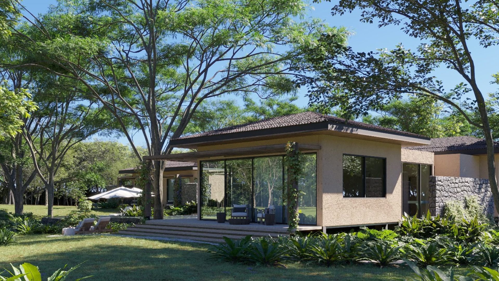 Modern tropical house with lush garden and shaded outdoor seating area.
