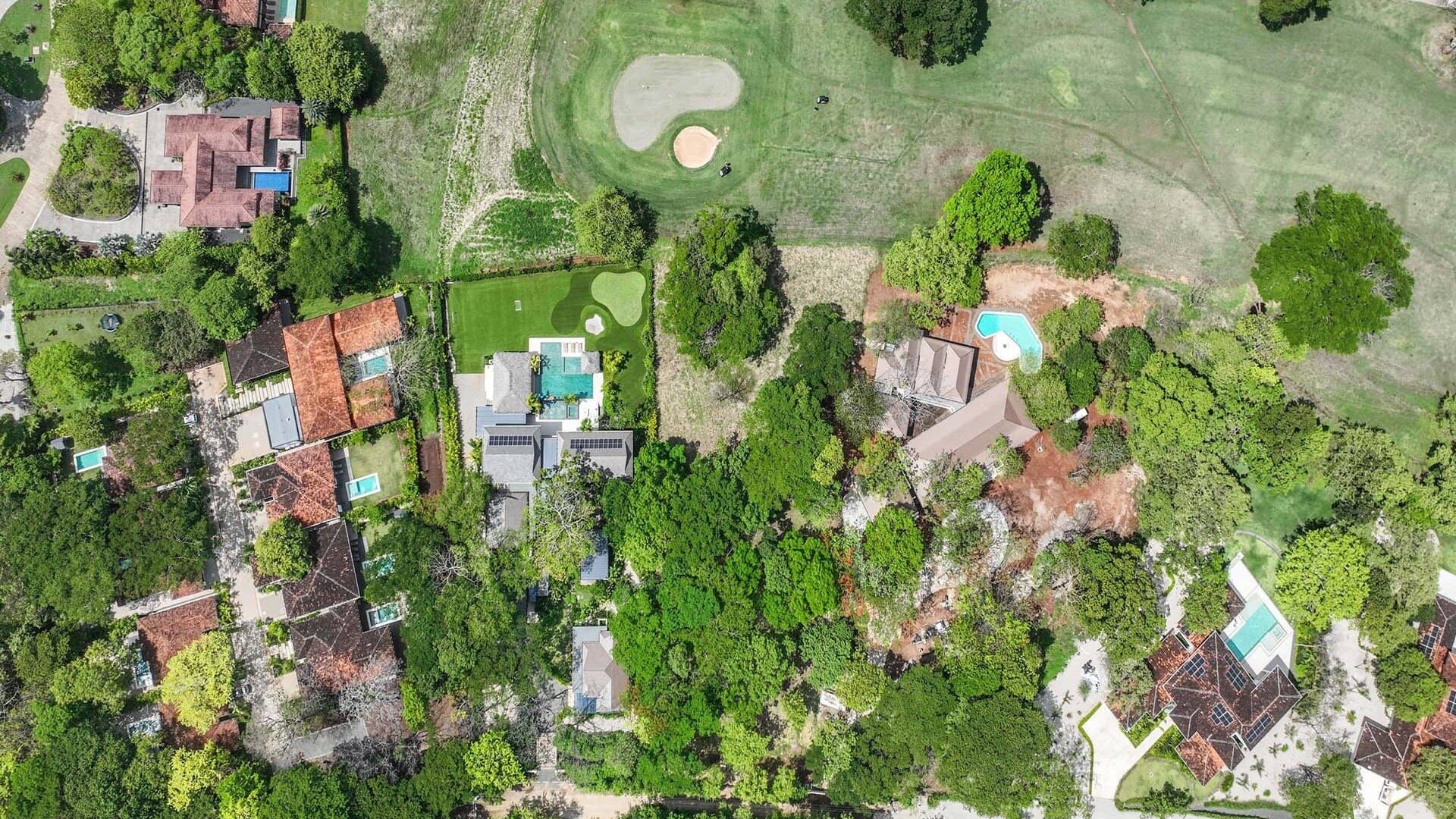 Lush residential neighborhood with swimming pools and expansive green golf course area.