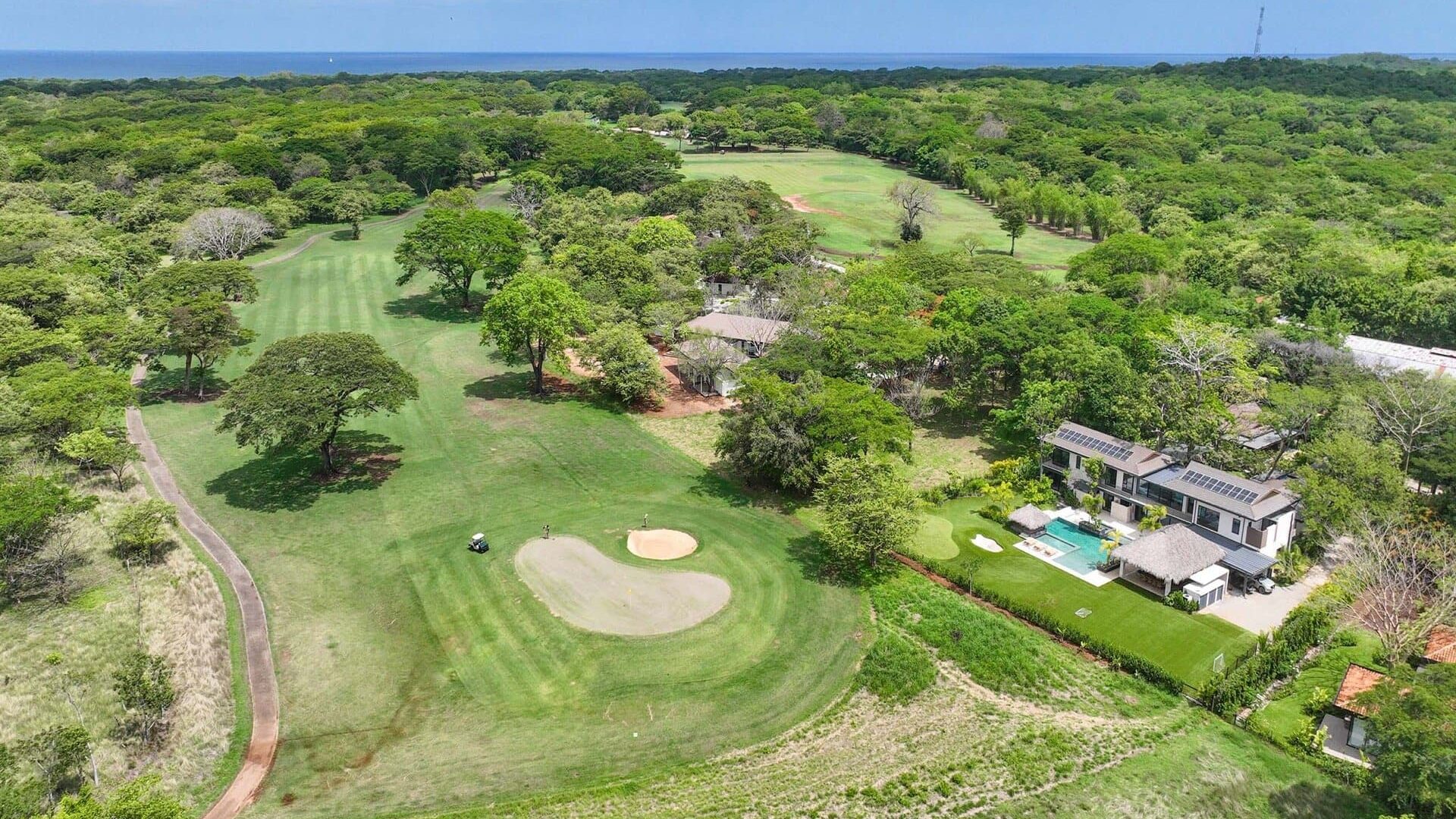Lush golf course with scenic ocean views and modern homes surrounded by greenery.