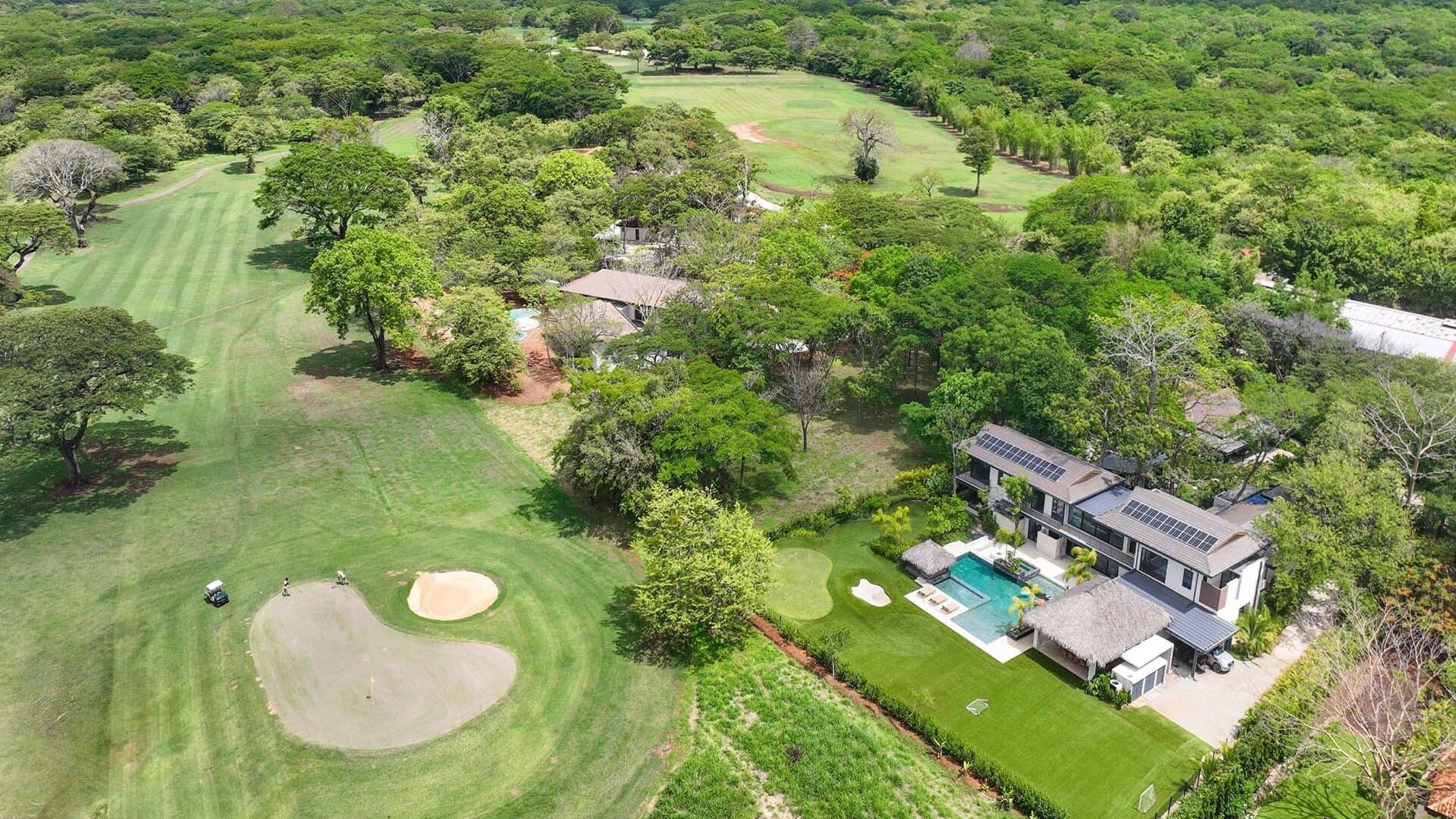 Luxury modern house with backyard pool on golf course, surrounded by lush greenery and trees.