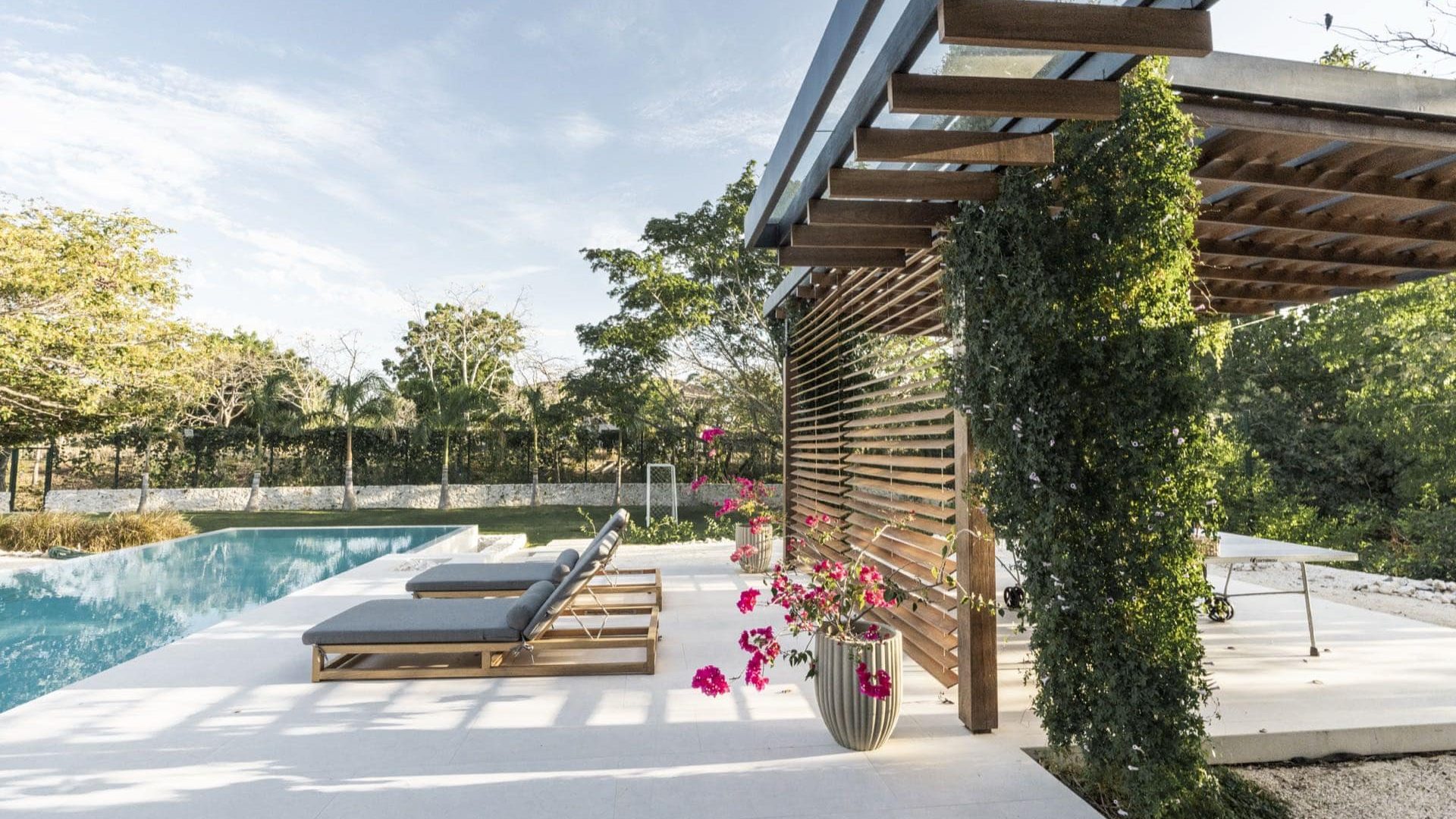 Modern outdoor pool area with sun loungers and lush greenery at Vida Pinilla.