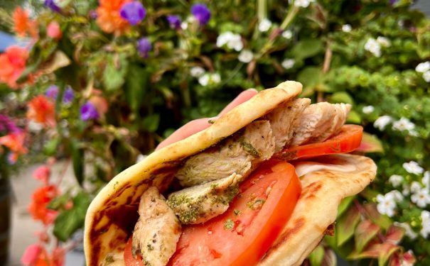 Enjoying a fresh grilled chicken pita sandwich outdoors at Bemus Point NY, perfect for a relaxing weekend getaway.