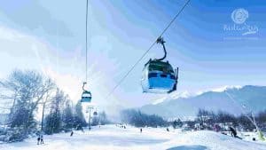A ski lift carrying people up a snowy mountain, surrounded by a picturesque winter landscape.