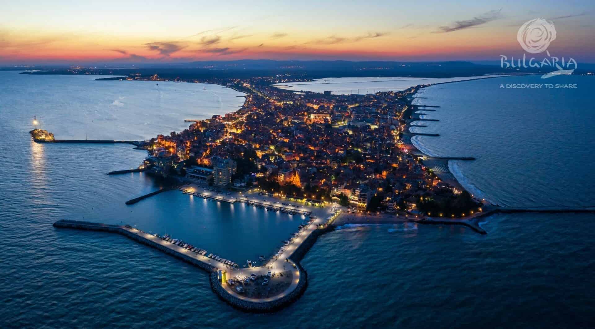 an aerial view of a city with lights on a body of water