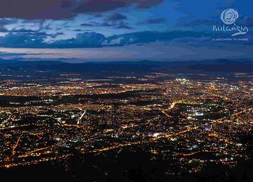 A breathtaking night view of the city, captured from a mountain peak. The city lights twinkle below, creating a mesmerizing sight.
