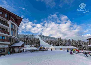 A ski resort with skiers and snowboarders enjoying the slopes on a sunny day.