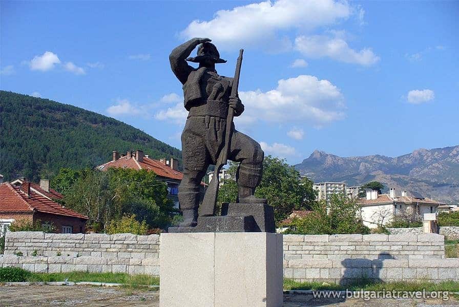 Military statue with rifle against mountain backdrop
